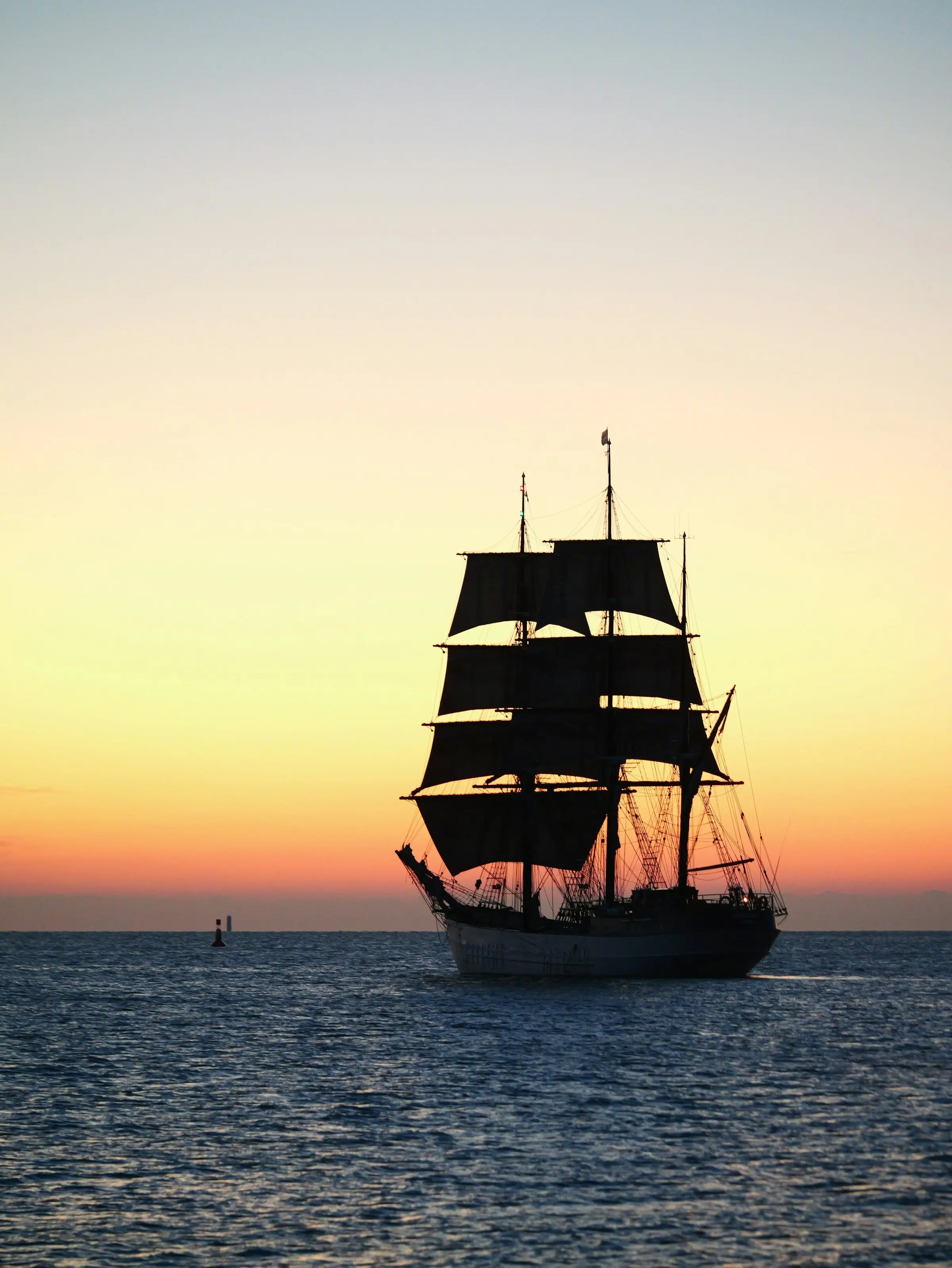 Dreimastiges Segelschiff als Silhouette vor dem Abendhimmel auf ruhiger See